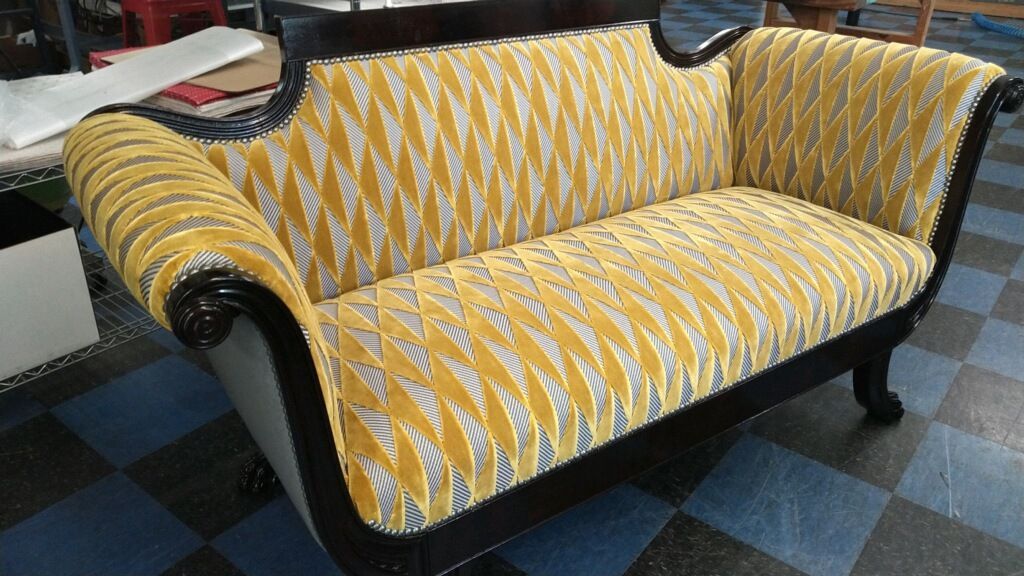 A yellow and black couch is sitting on a checkered floor