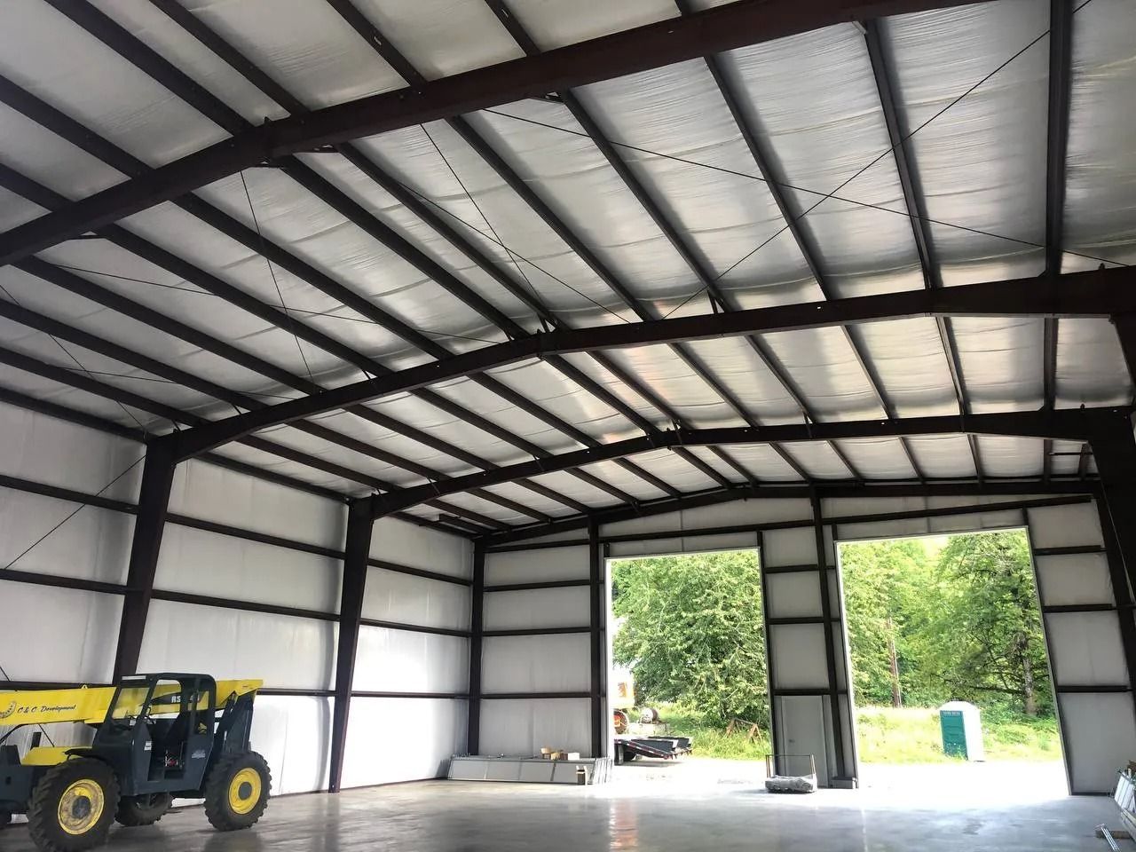 Inside view of a steel-framed warehouse with a large open door and machinery inside.