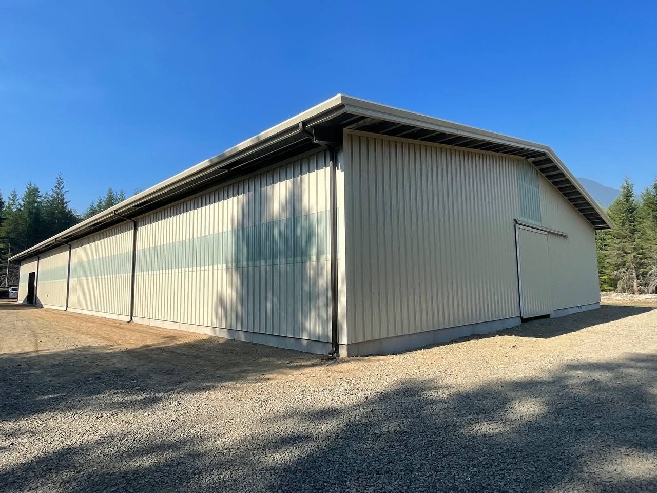 Light beige metal building with a gravel base, under a blue sky.