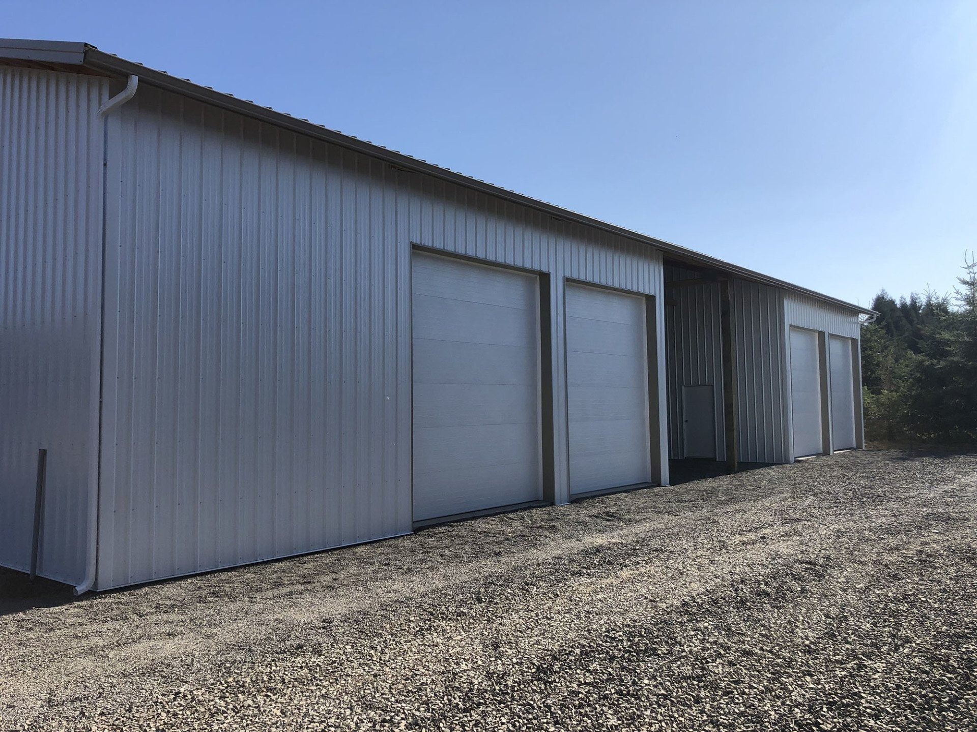 Metal warehouse with three garage doors against a blue sky.