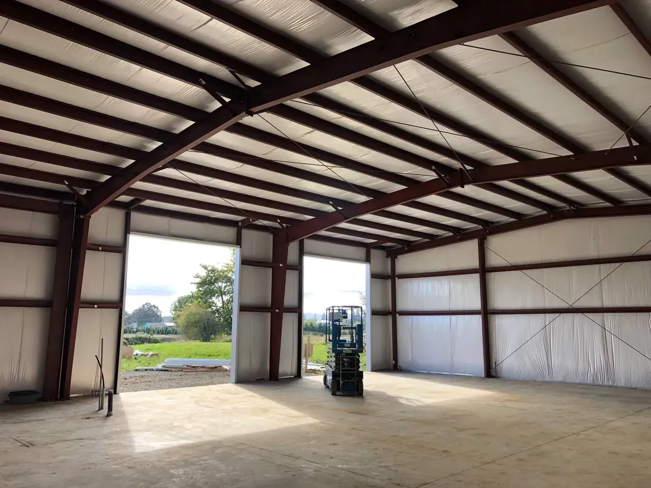 Interior of a metal building with large open doors.  A small forklift sits inside.