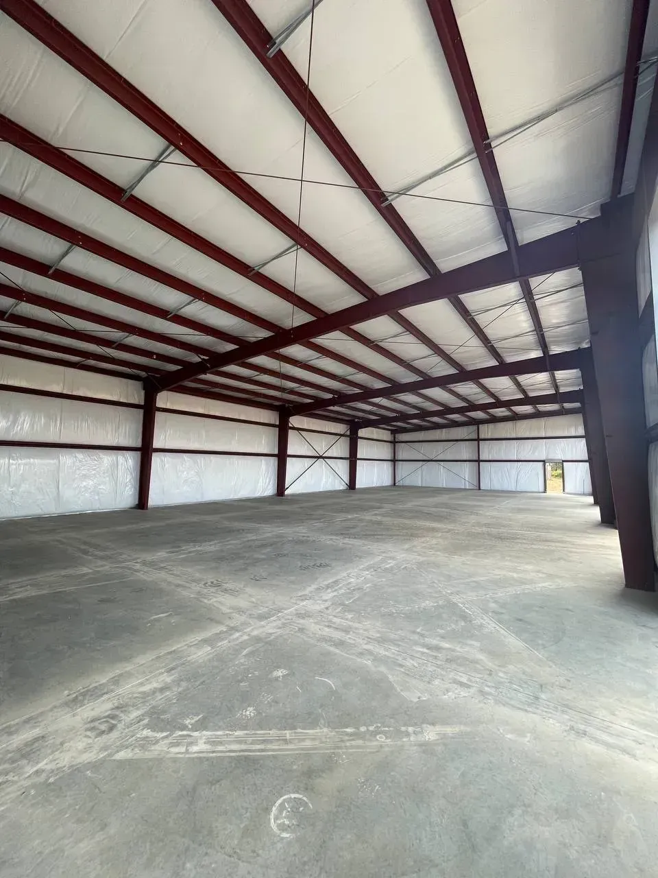 Empty warehouse interior with metal beams and concrete floor.