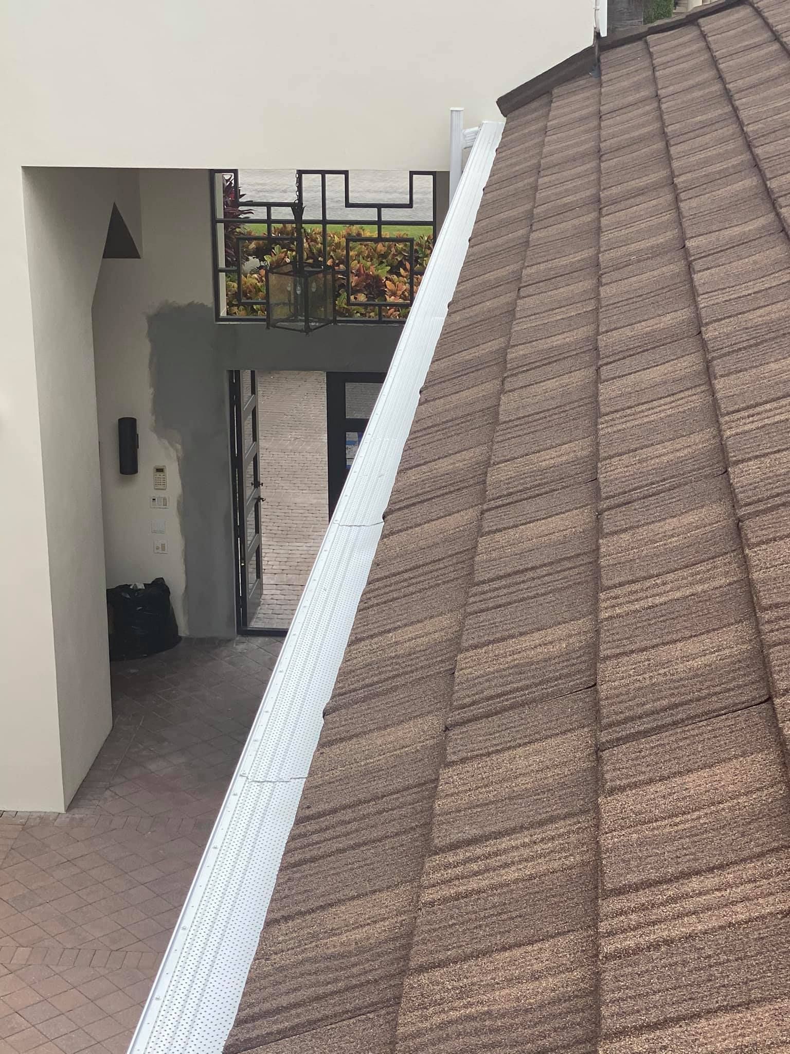 Roofline view of a courtyard with white walls, a door, and a balcony railing under a tiled roof