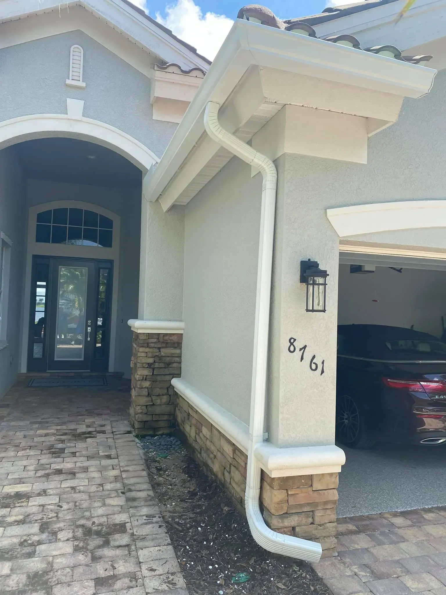 House entrance with stone-accented columns, arched doorway, and a garage opening on the right.