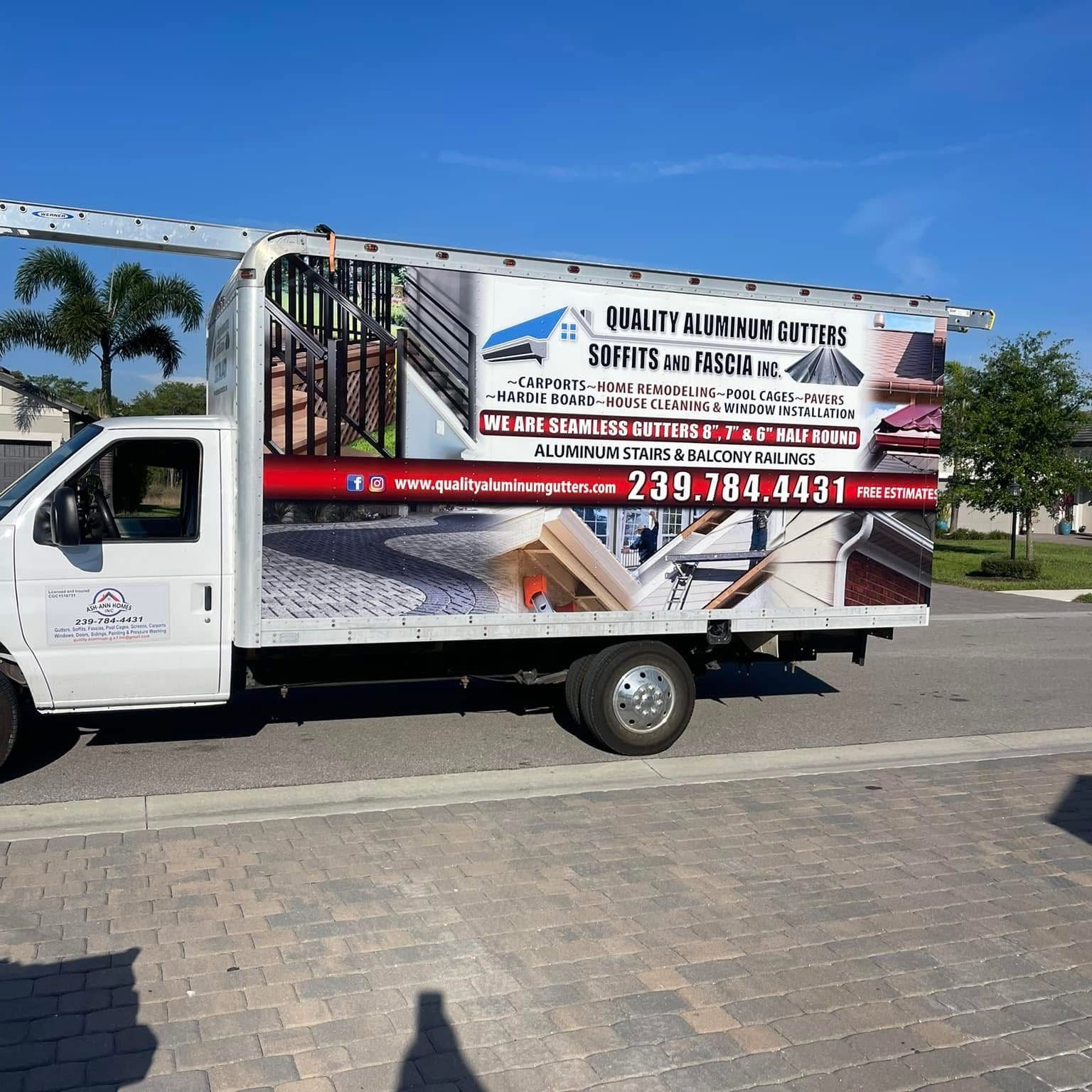 White box truck with large aluminum gutter advertising driving on a sunny street near palm trees