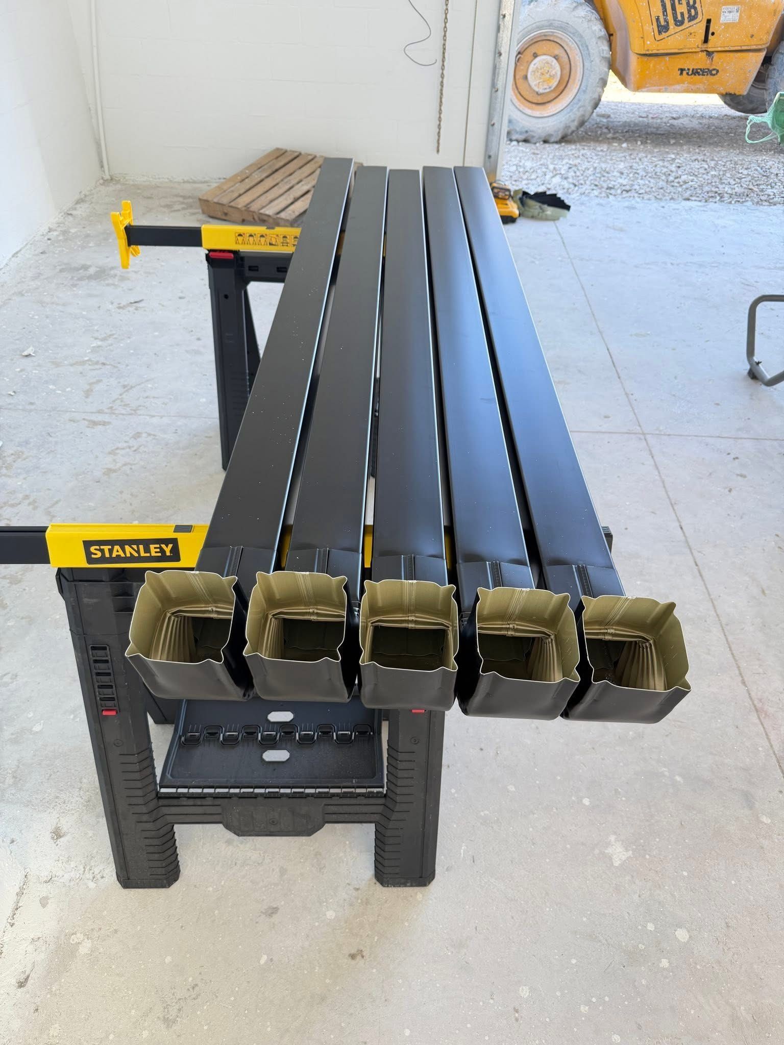 Black metal workbench with five slotted bars on a yellow and black stand in a garage area