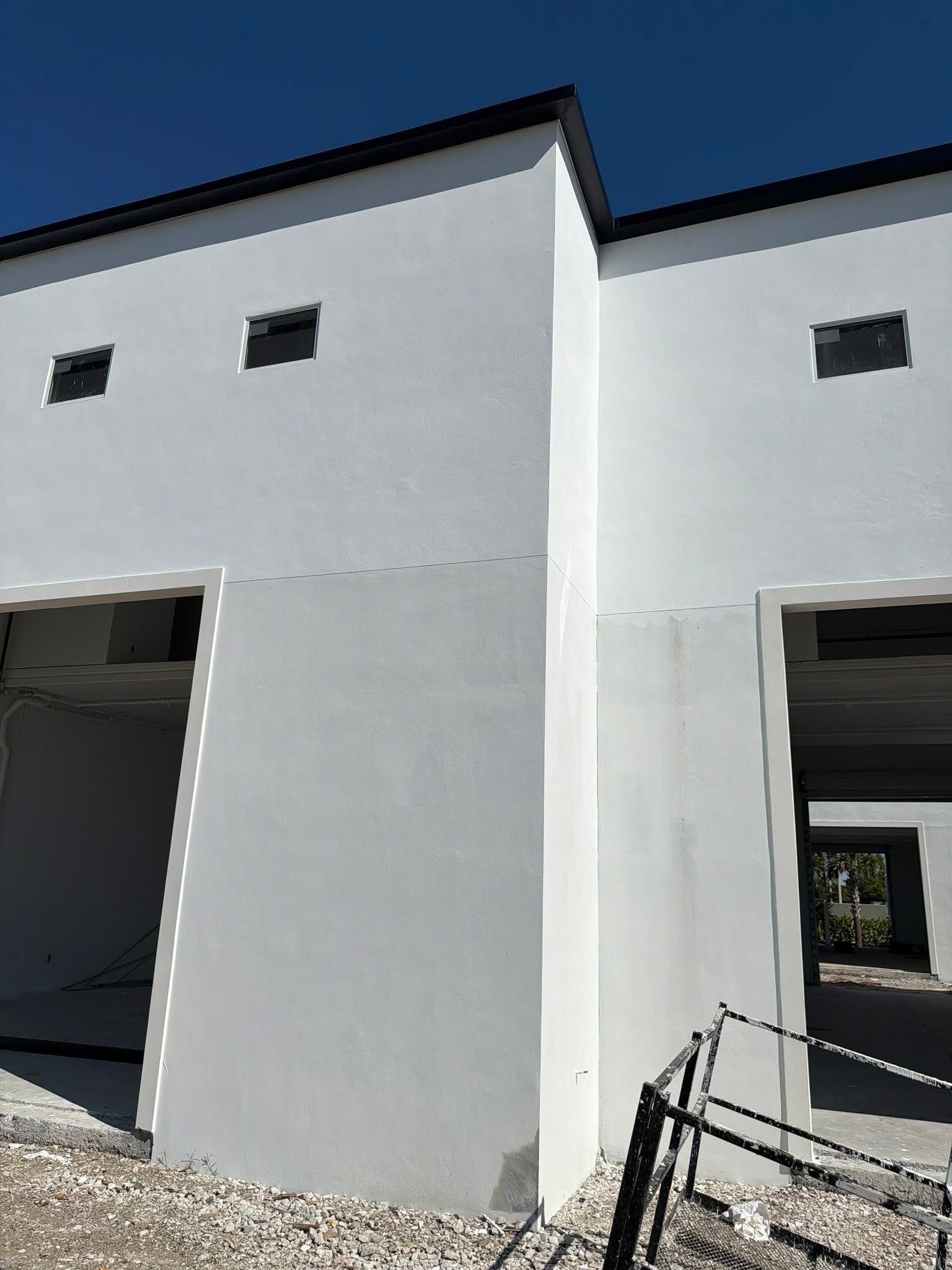 White building facade with two open garage-style doorways under a blue sky