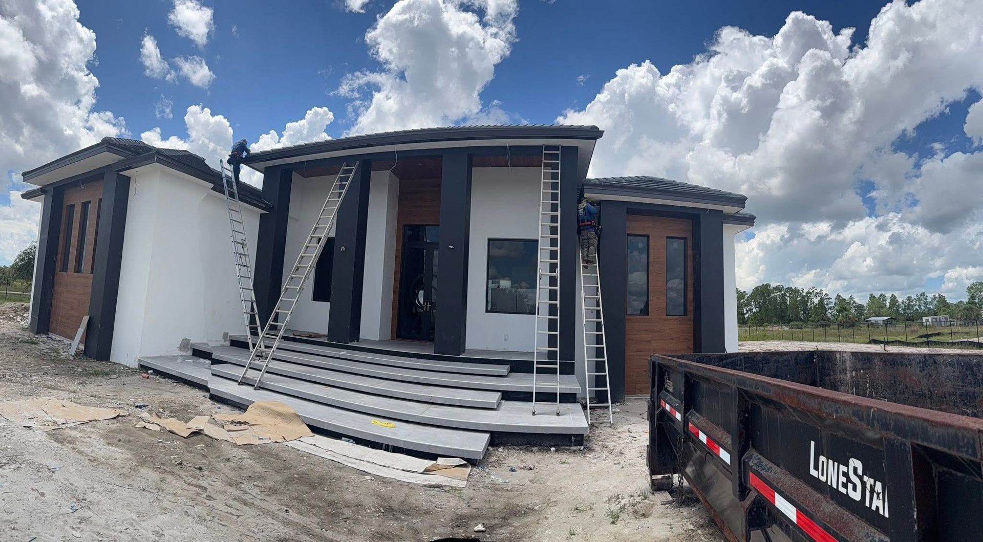 New house under construction with white and dark exterior, front steps, and a truck parked beside it
