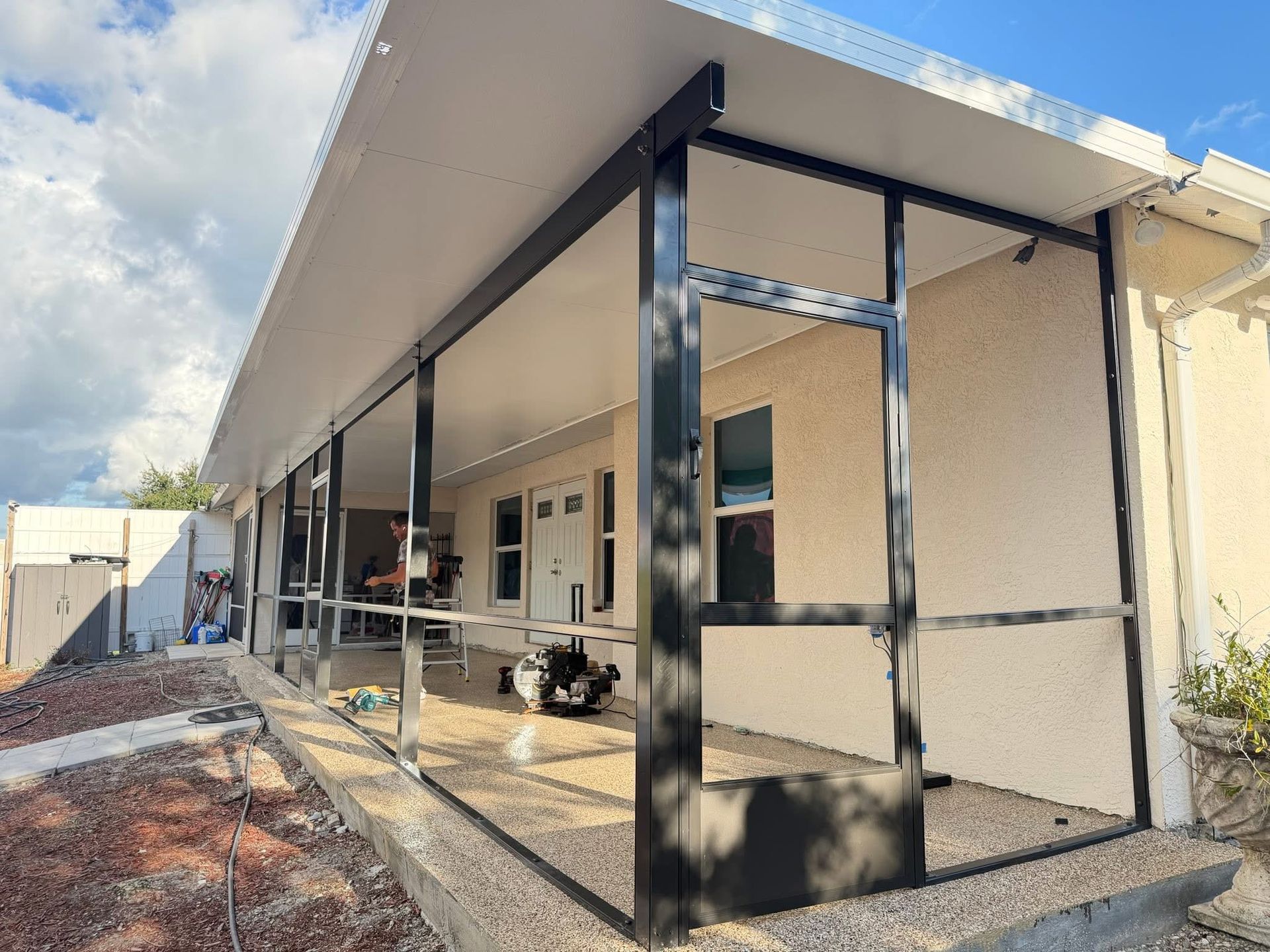 Partially built house with metal framing and a covered walkway on a dirt lot