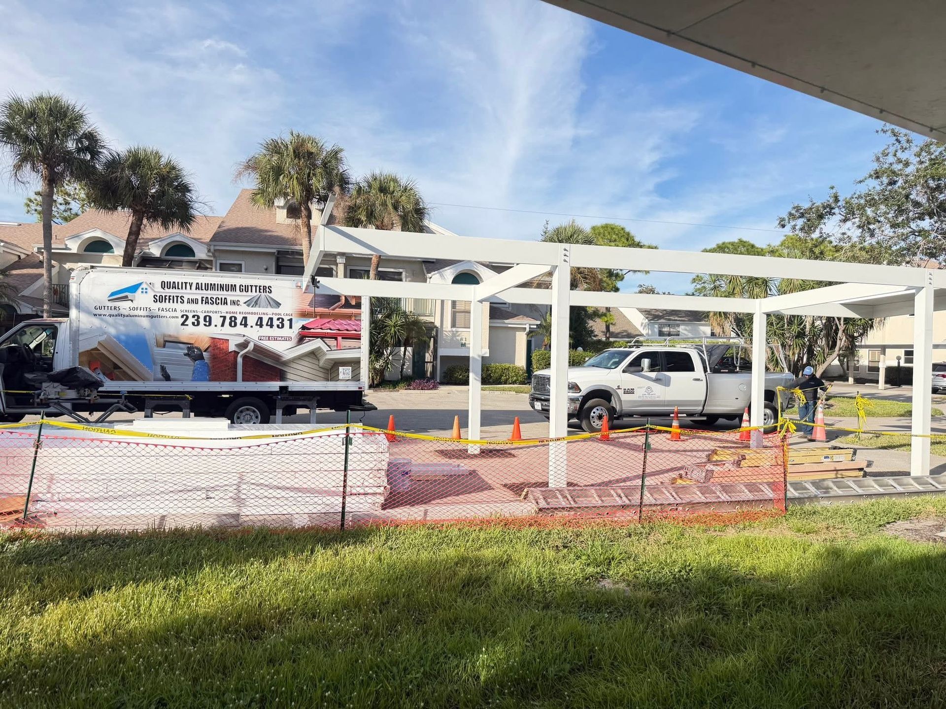 Workers building a white pergola structure beside a truck and van at a park