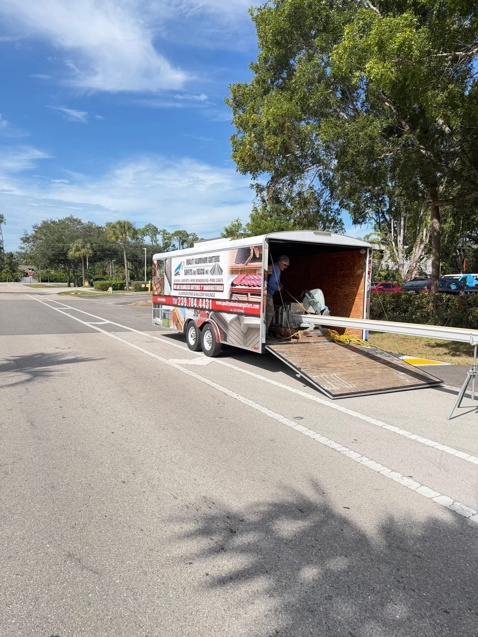 Roadside truck with open cargo bay and ramp beside a paved street under a blue sky
