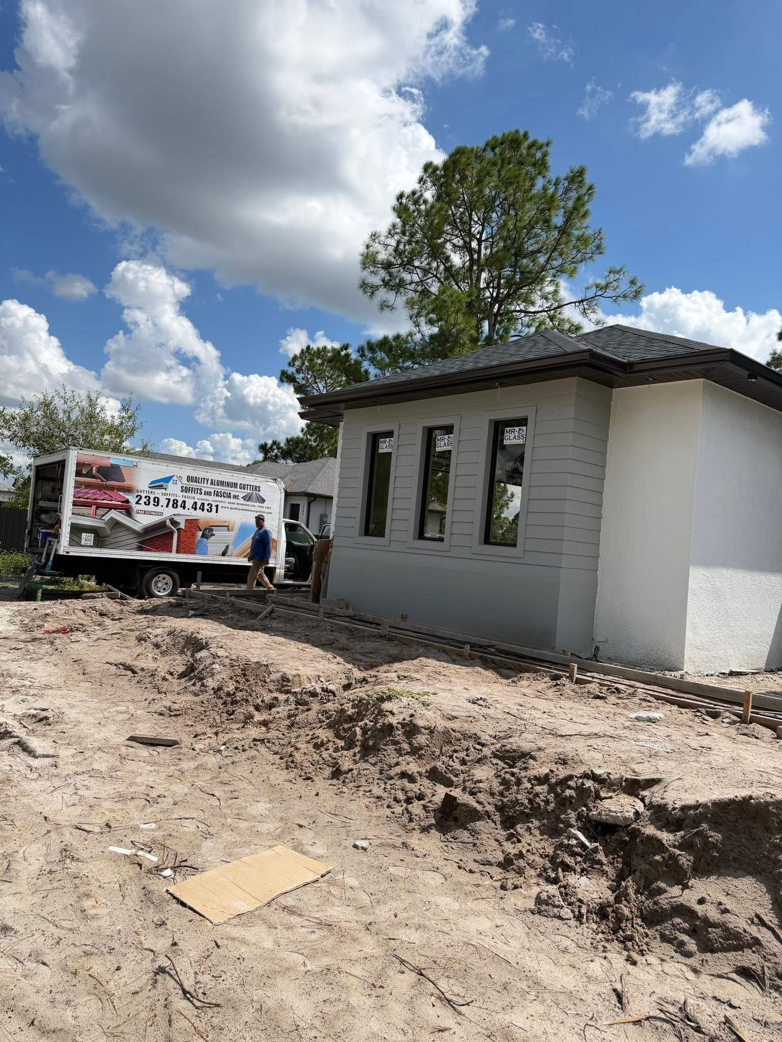 Partially built house with truck on muddy construction site under cloudy sky