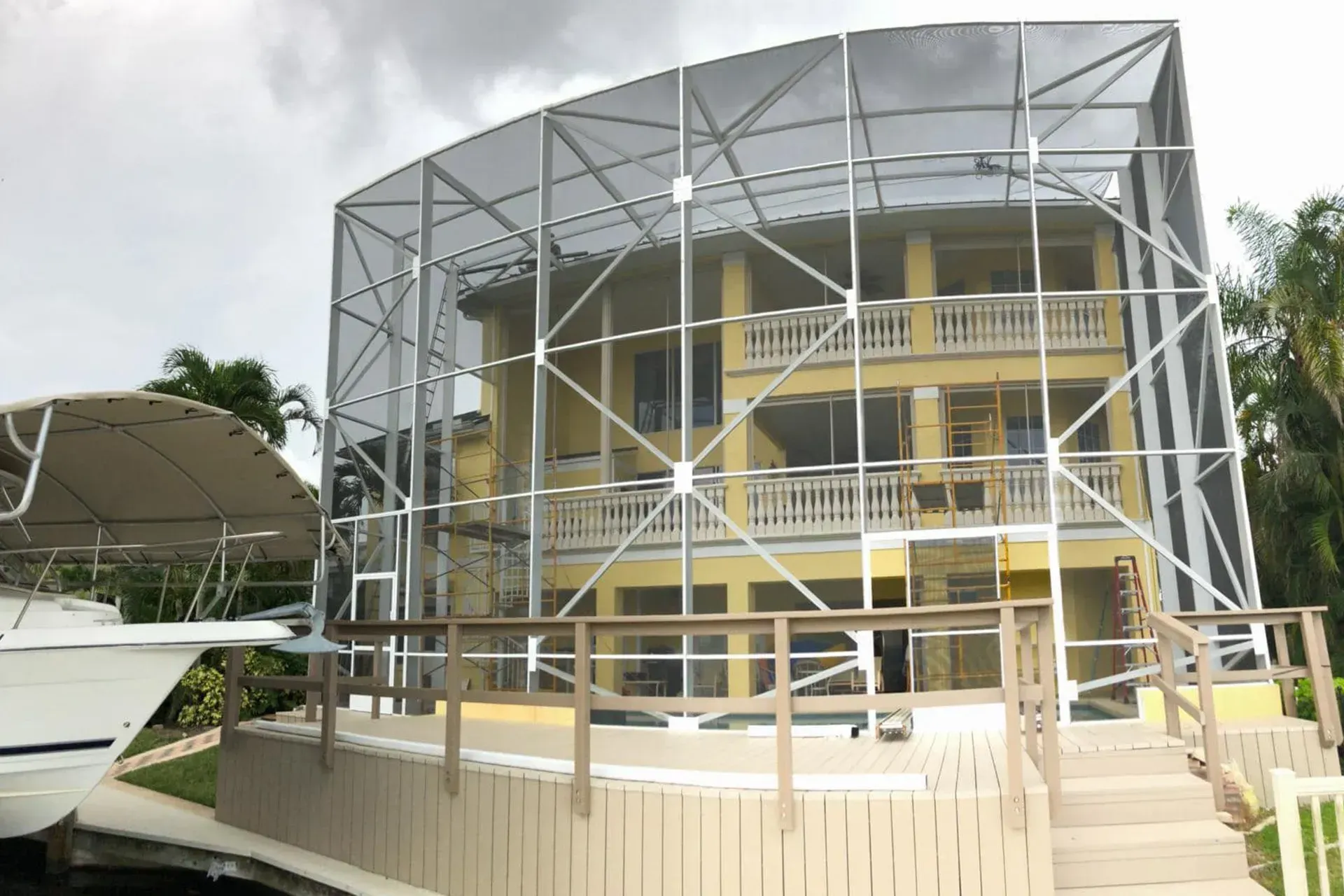 Yellow multi-story building encased in metal scaffolding beside a boat in a marina