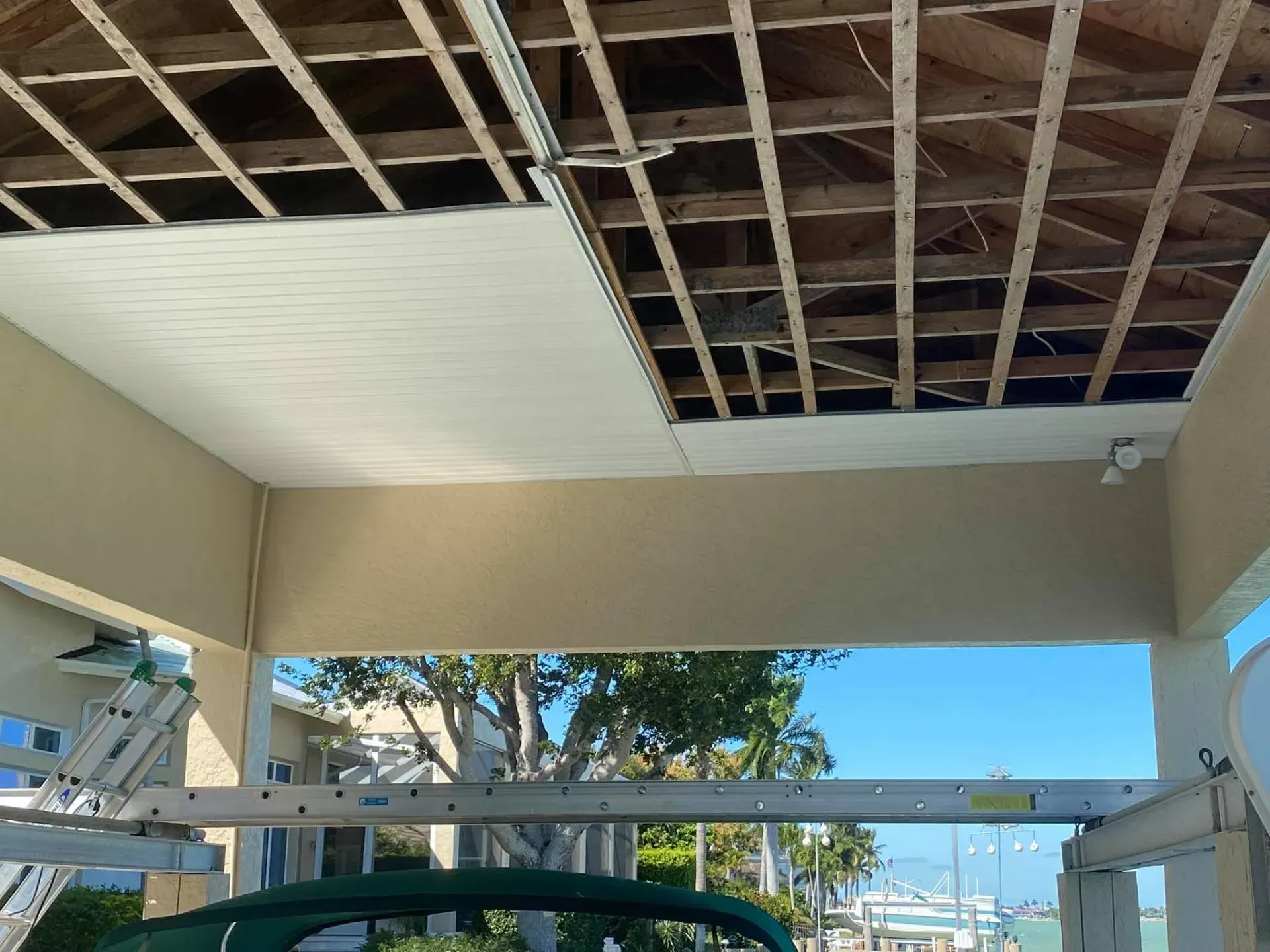 Partially finished porch ceiling with exposed rafters and a large opening to a sunny waterfront view