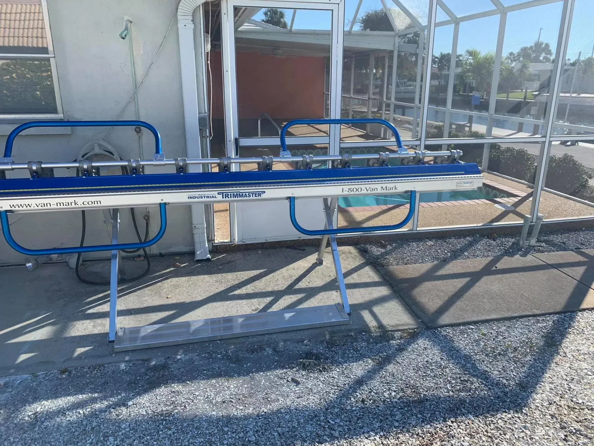 Empty school picnic table with blue metal benches beside a chain-link fence in bright sunlight