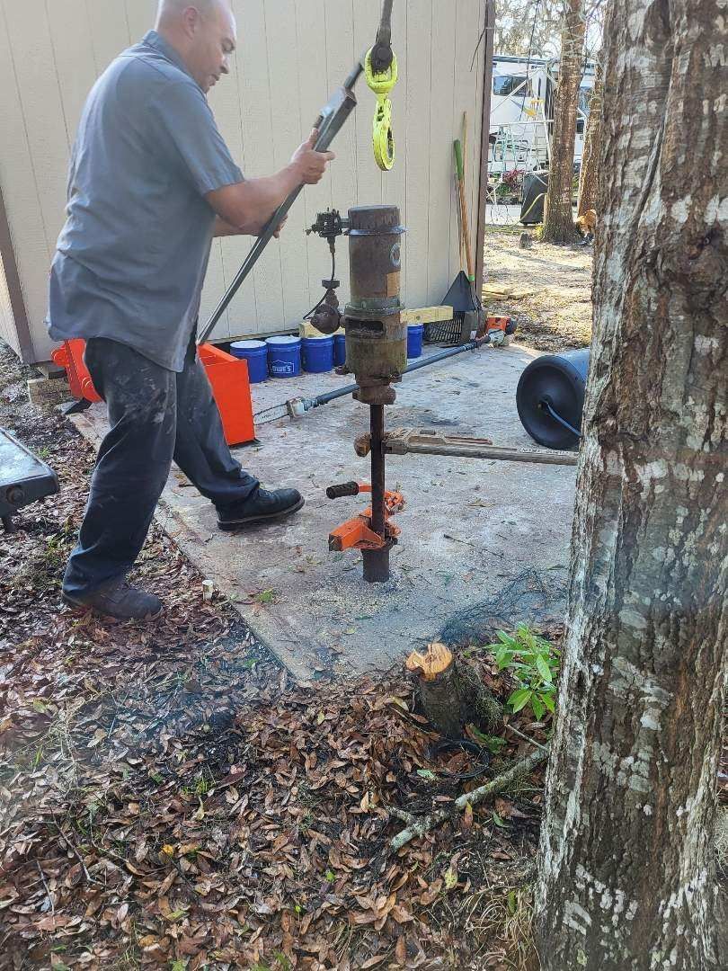 A man is using a drill to dig a hole in the ground.