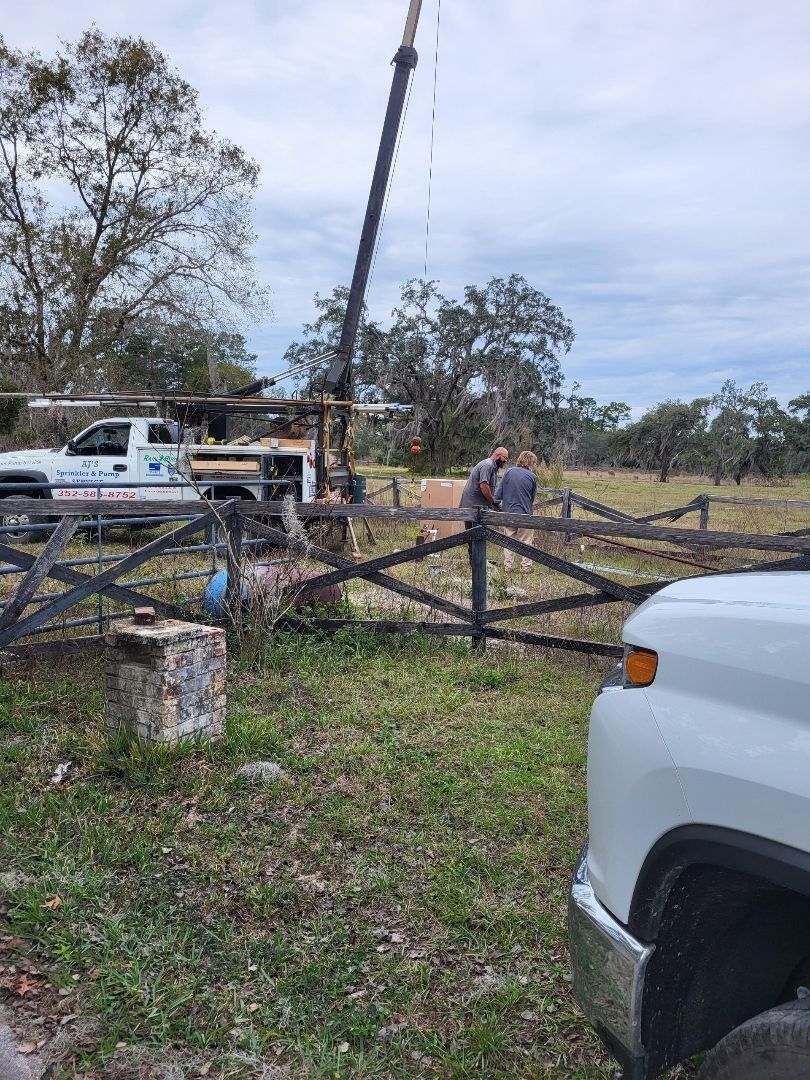 A white truck is parked in a grassy field next to a crane.