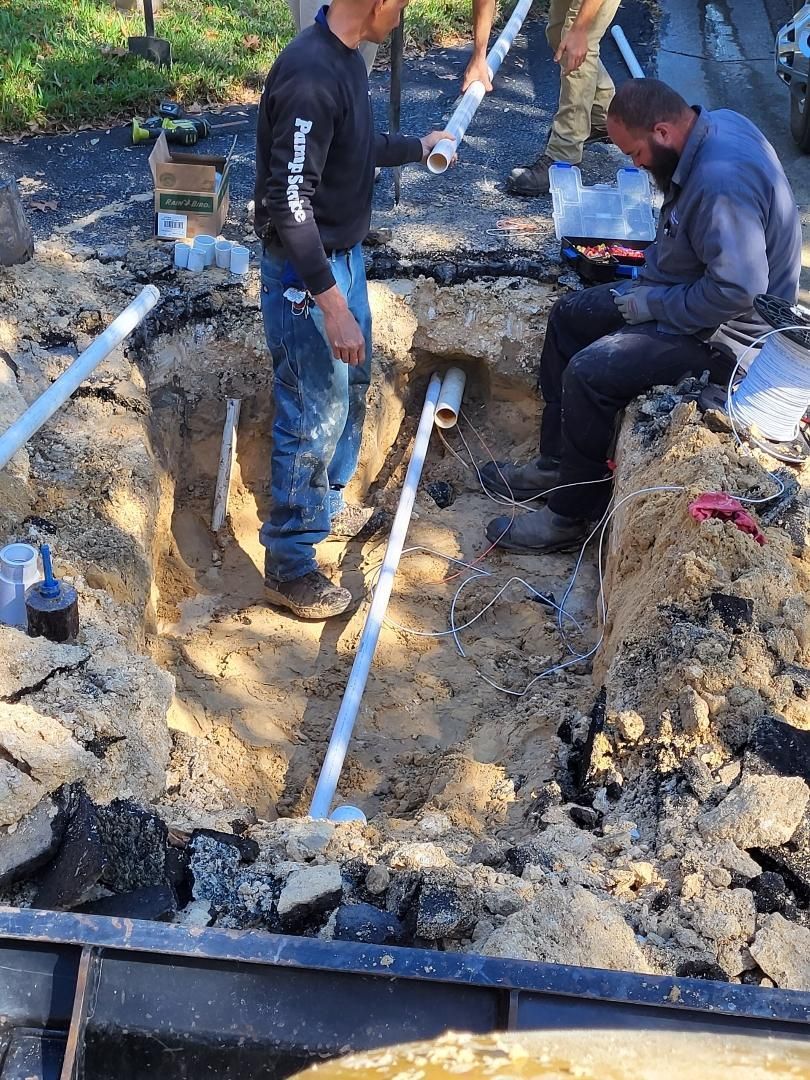 A group of men are working on a pipe in the dirt.
