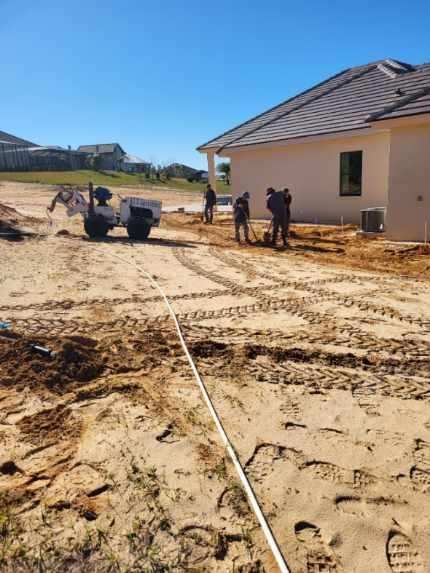 A group of people are standing in the dirt in front of a house.