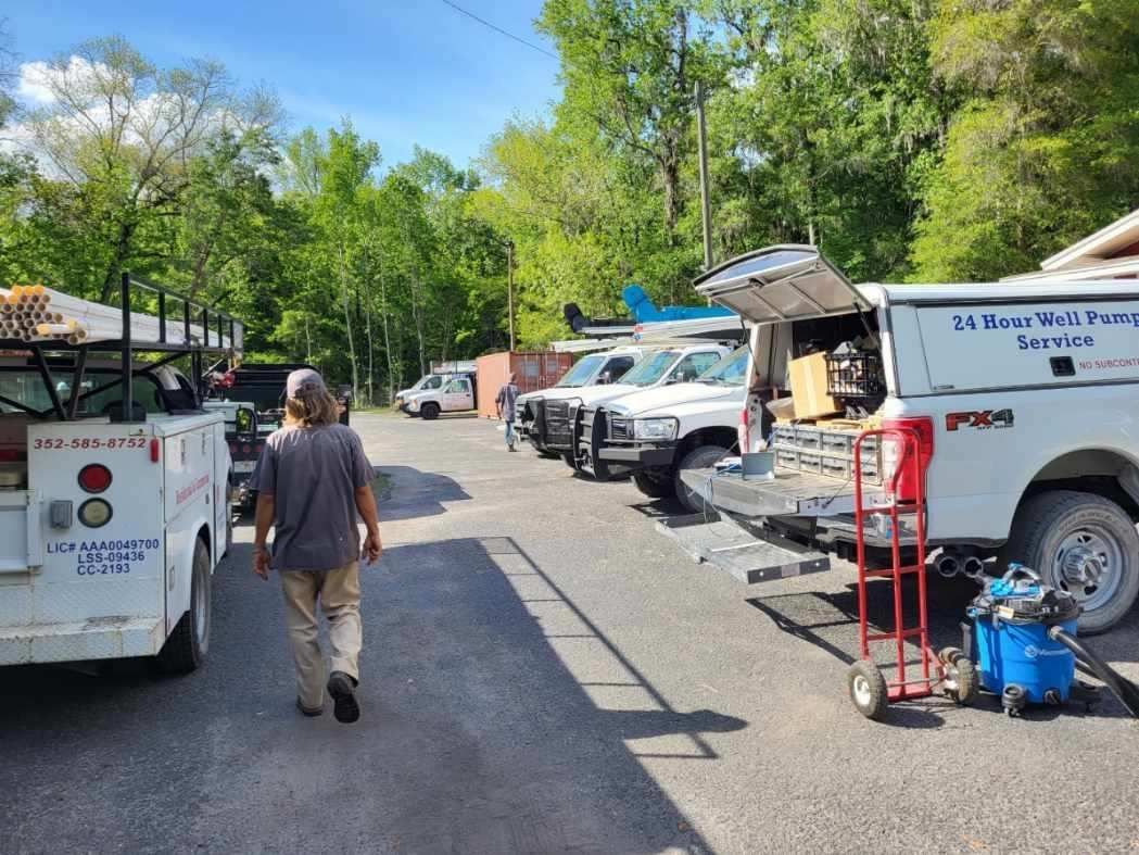 A man is walking down a street next to a row of trucks.
