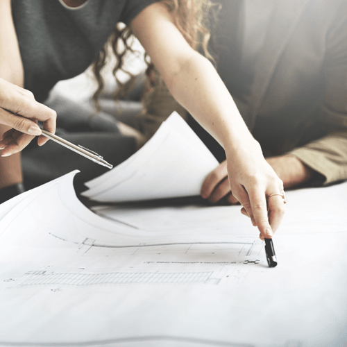 A woman is pointing at a piece of paper with a pen