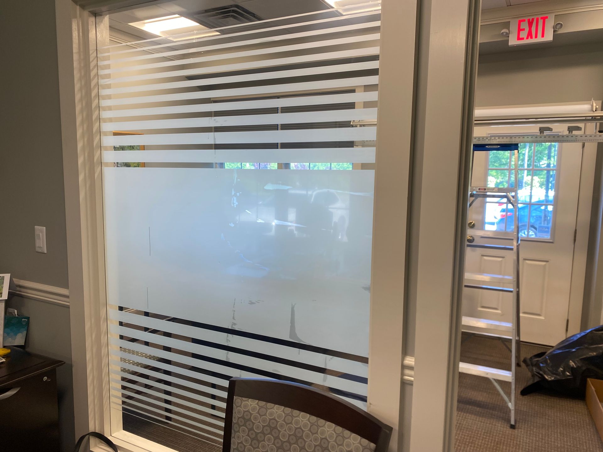 A room with a ladder and an exit sign on the wall.