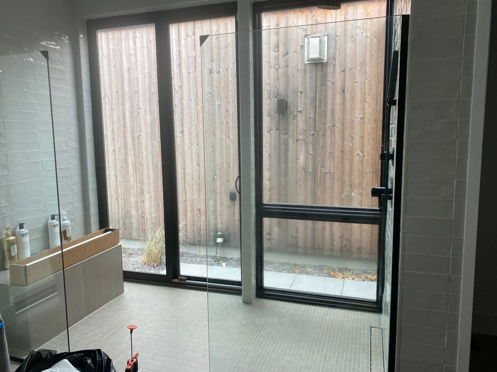 A bathroom with a lot of windows and a wooden fence in the background.