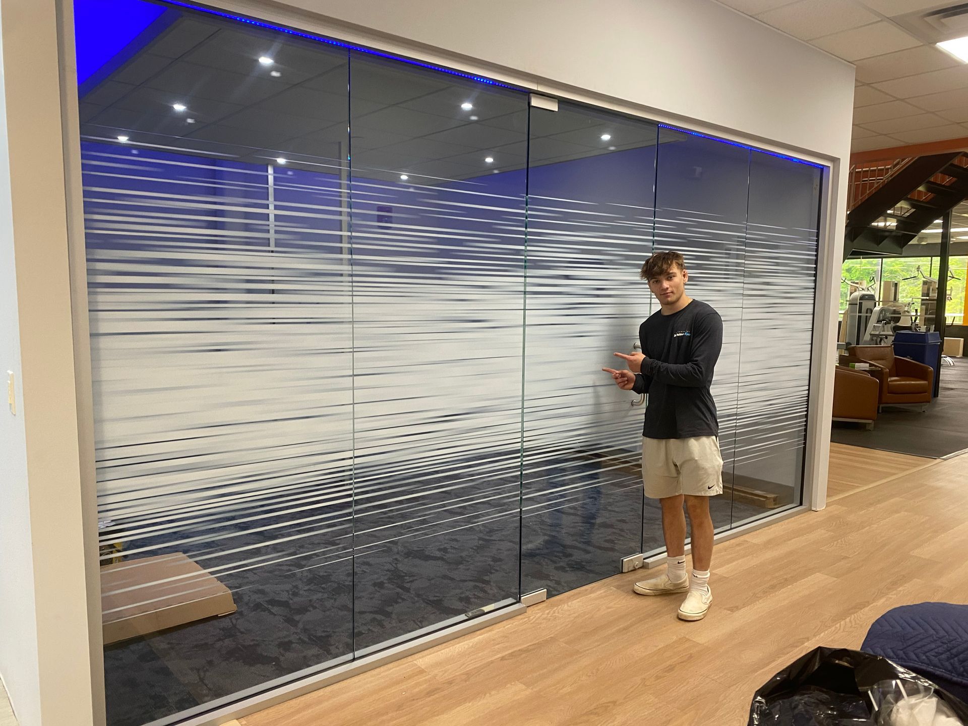 A man is standing in front of a glass wall in a room.