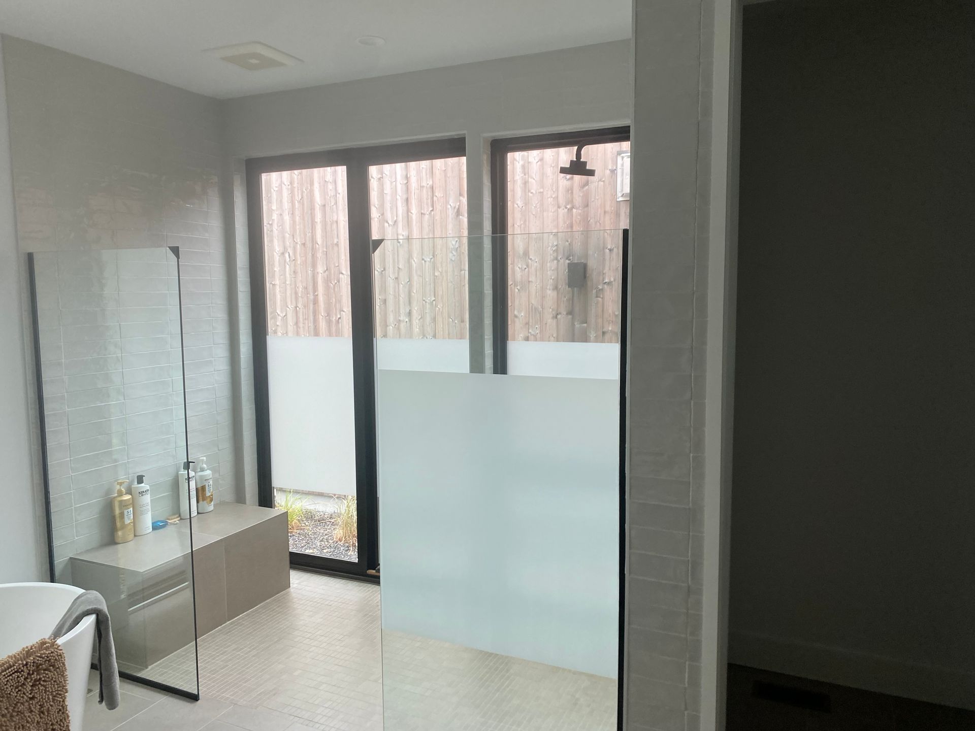 A bathroom with a walk in shower and a large mirror.
