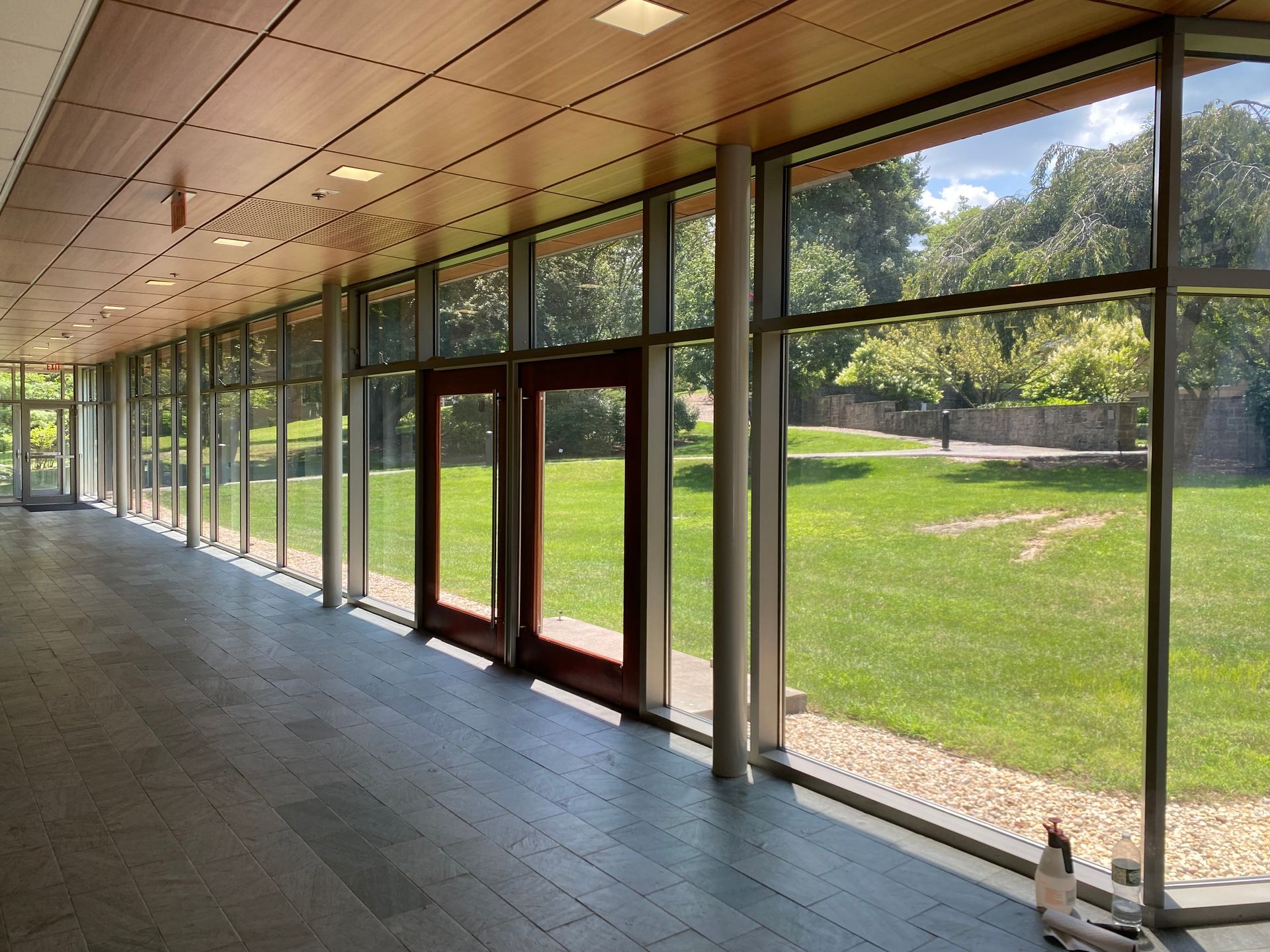 A long hallway with lots of windows looking out to a grassy field