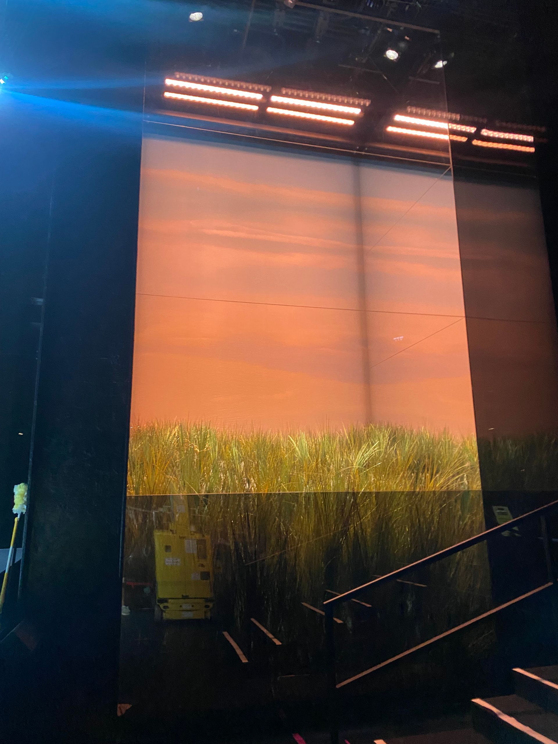 A large screen with a picture of a field on it is on a stage.