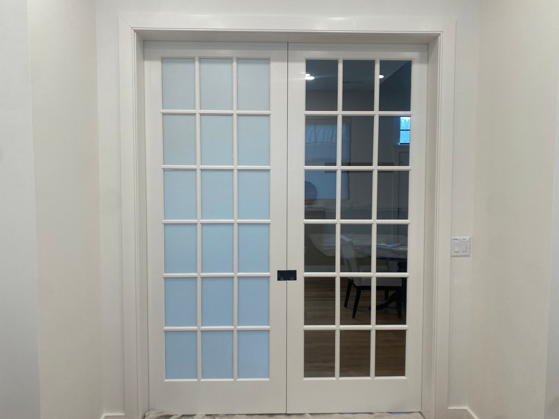 A pair of sliding glass doors in a hallway leading to a dining room.