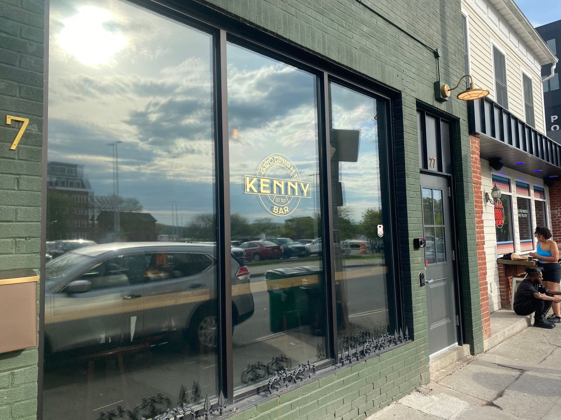 A green brick building with a car parked in front of it.