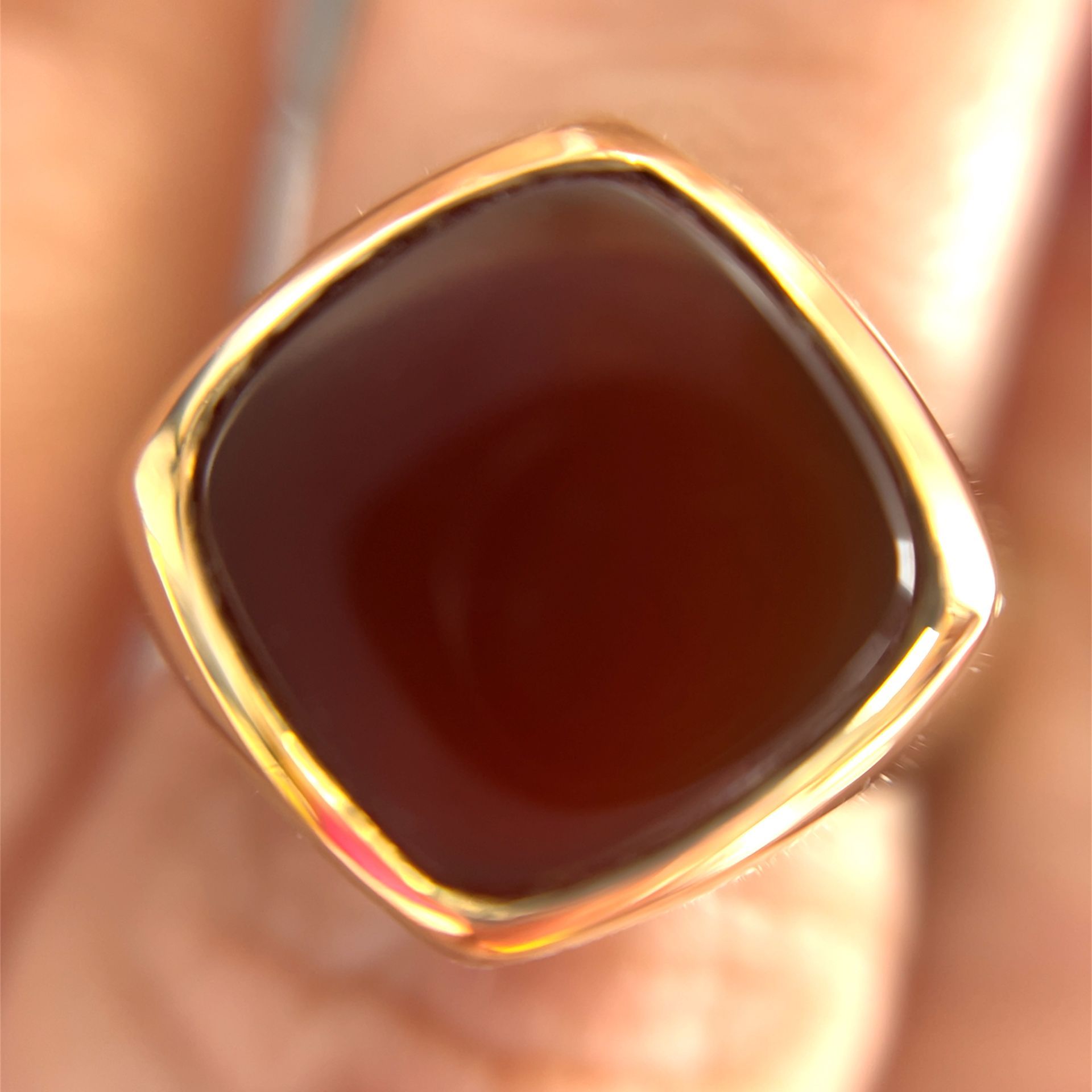 Gold ring with a square, dark brown stone.