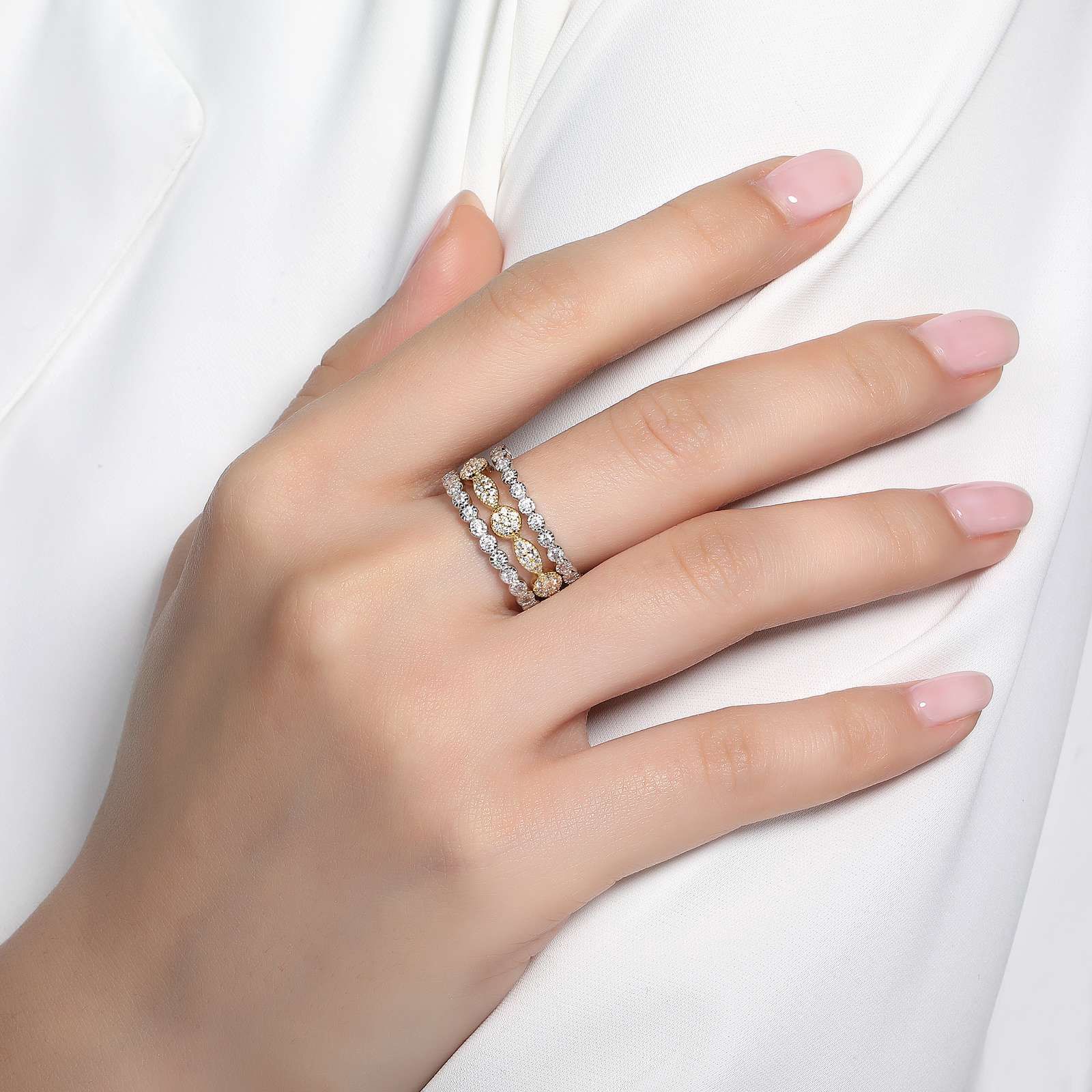 Hand wearing a three-band ring with gold and diamond details.