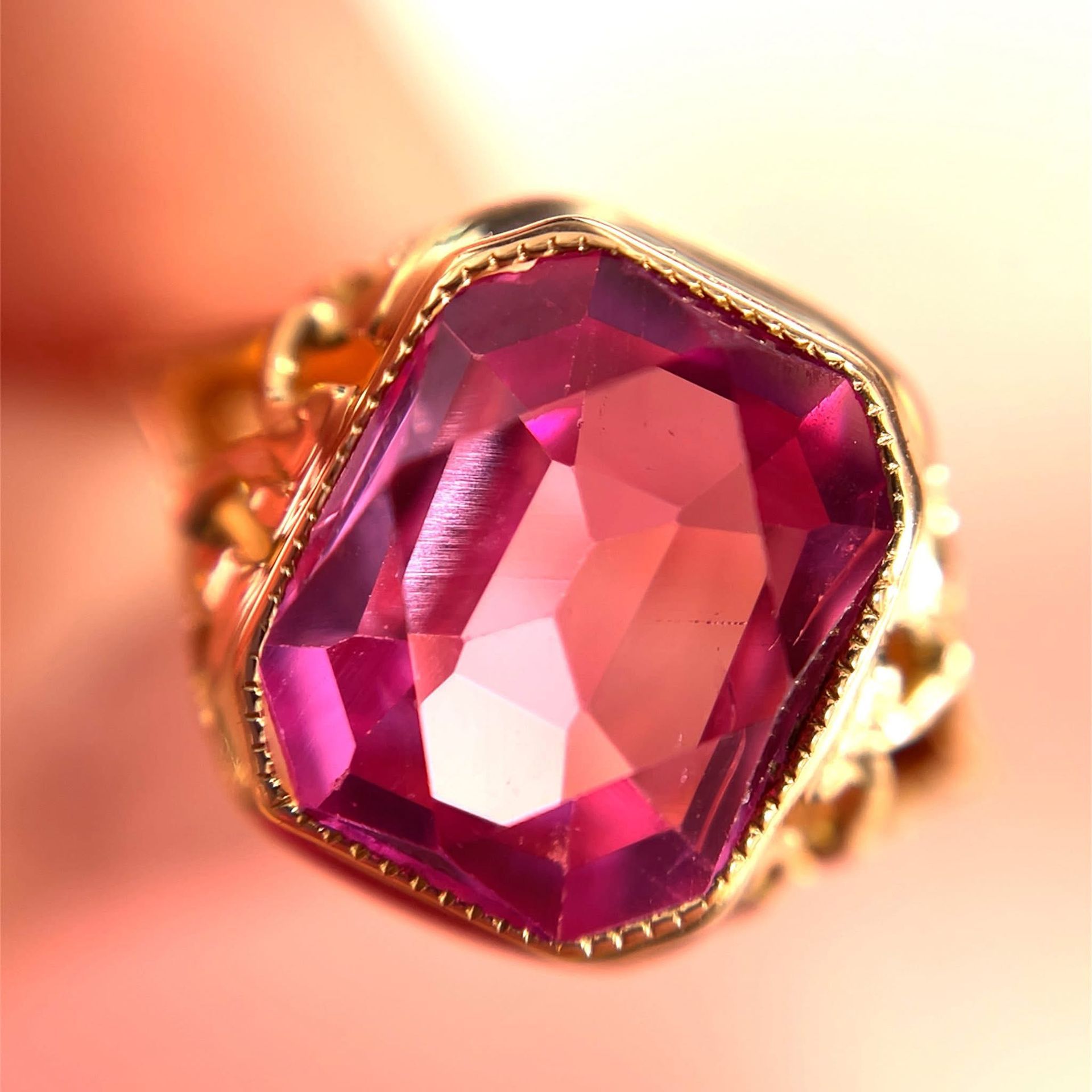 Gold ring with a large, faceted pink gemstone.