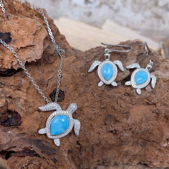 Silver turtle jewelry set with turquoise center stones on wooden background.