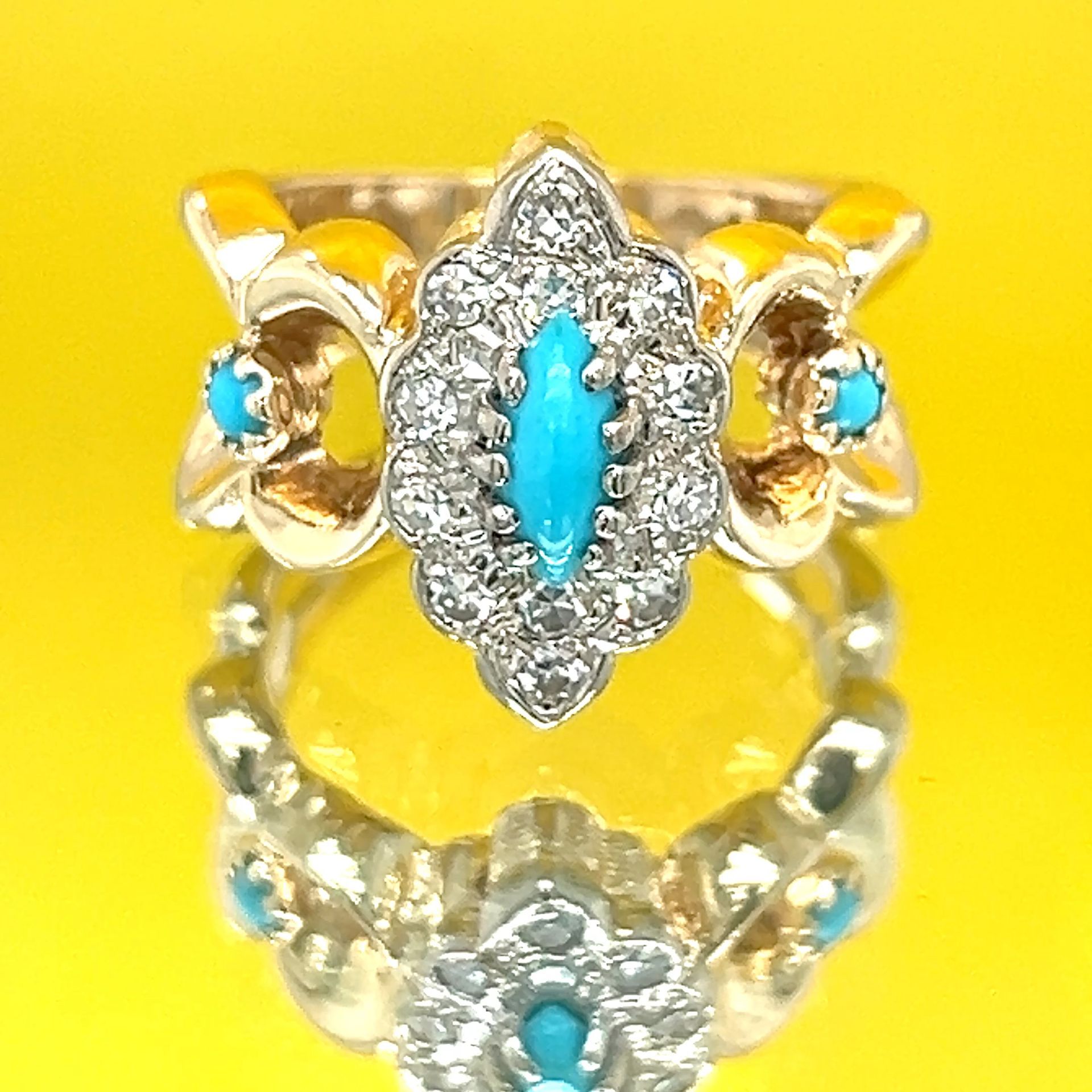 Gold ring with a turquoise center stone surrounded by diamonds and smaller turquoise accents.