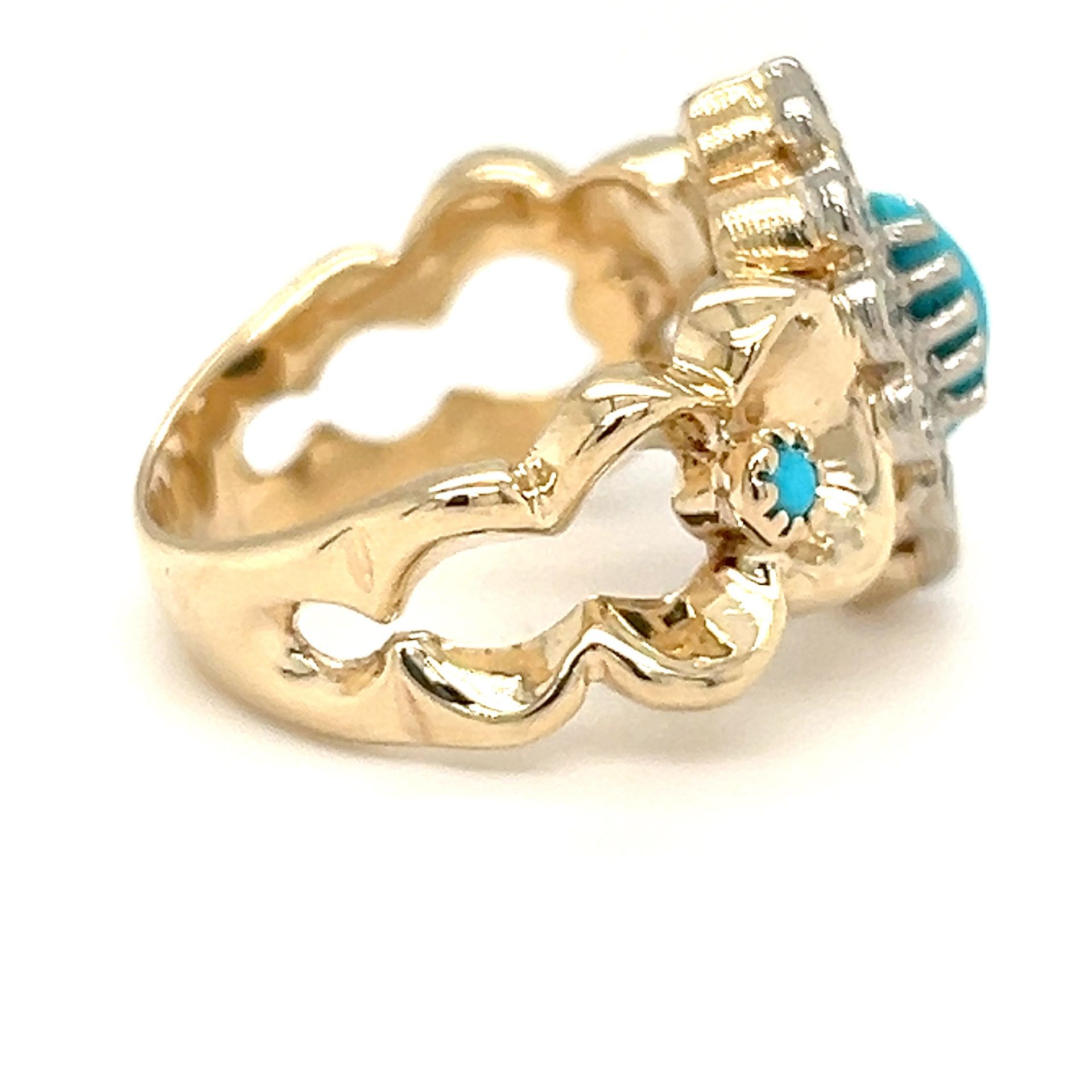 Gold ring with a turquoise stone in the center, and a floral design around it.