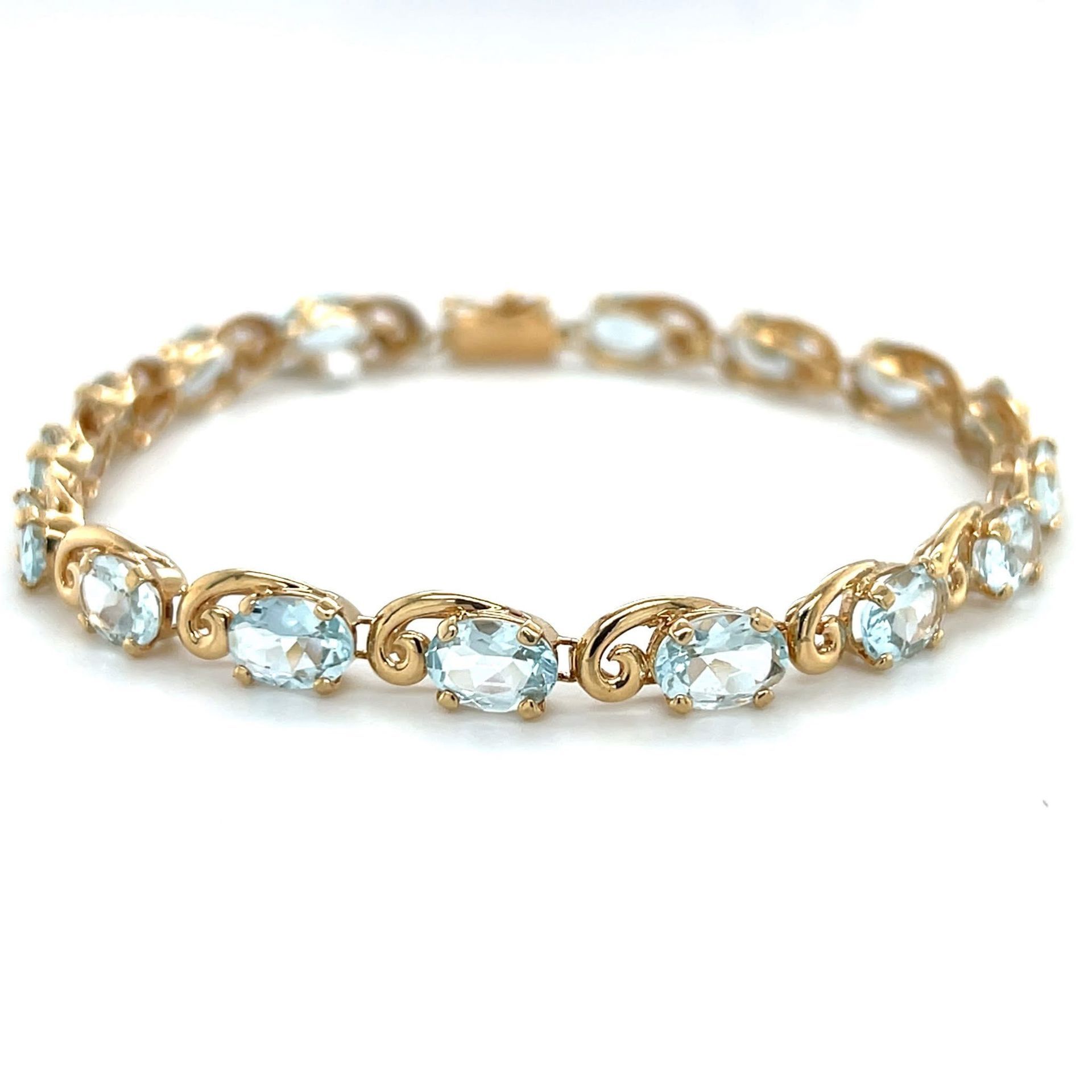Gold bracelet with oval, light blue gemstones.