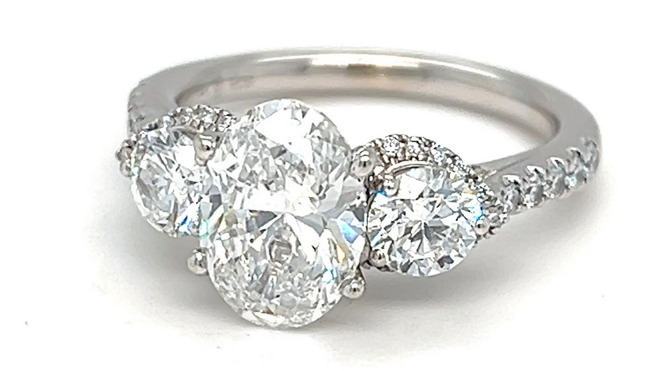 Two diamond rings on a marble surface; the engagement ring has a flower-like setting.