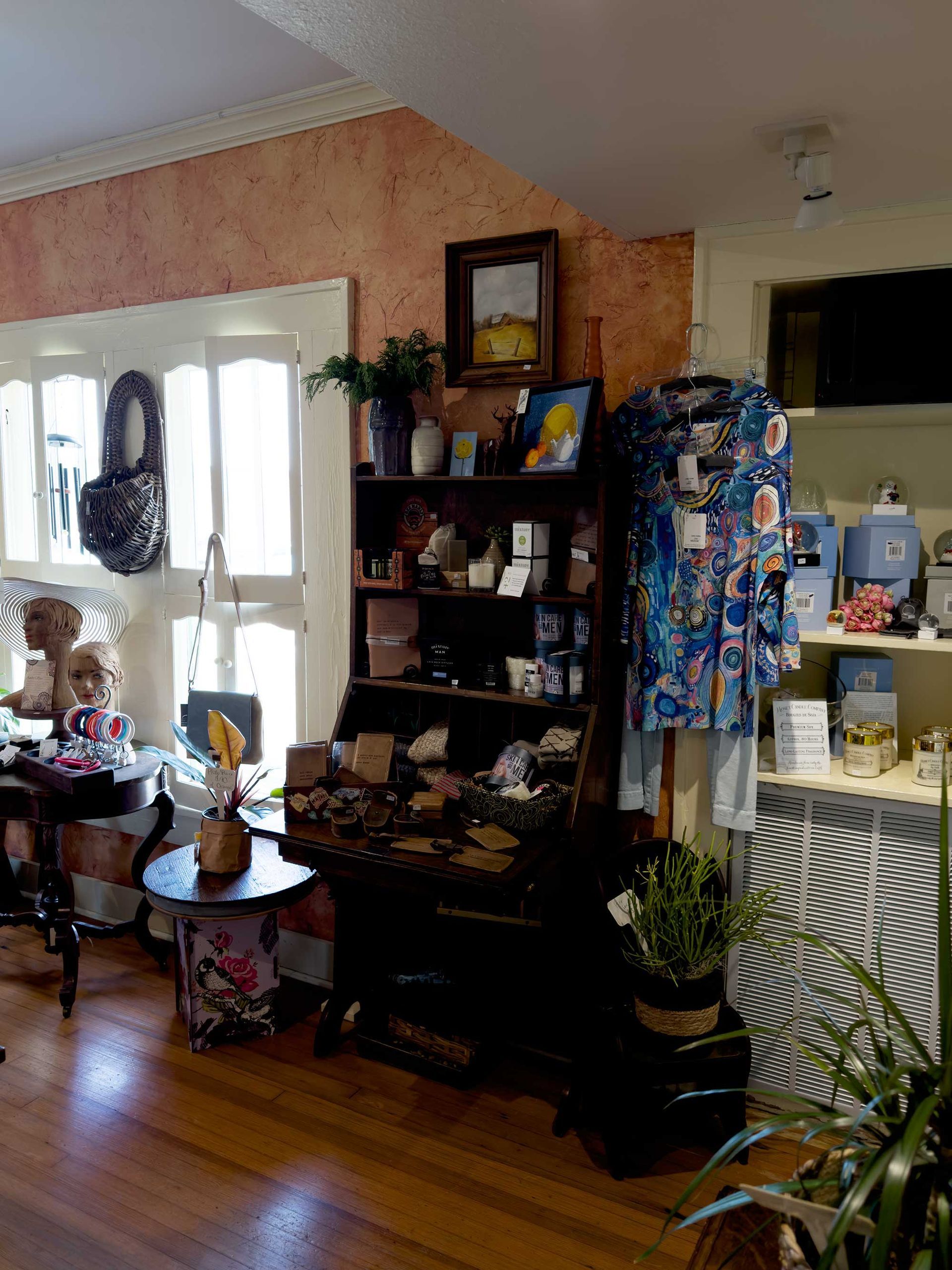 A cluttered interior shop corner features a dark wooden shelf unit, a blue patterned tunic, and decorative items.