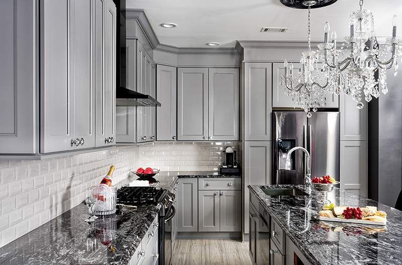 Gray kitchen with granite countertops, stainless steel appliances, and a chandelier.