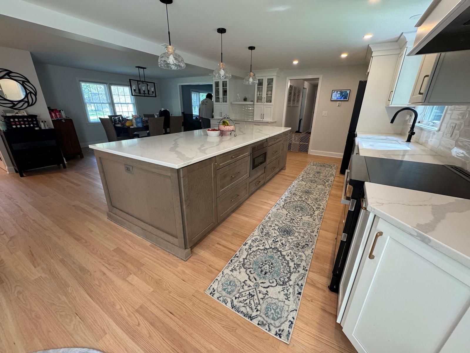 Modern kitchen with large island, light wood floors, and white countertops.
