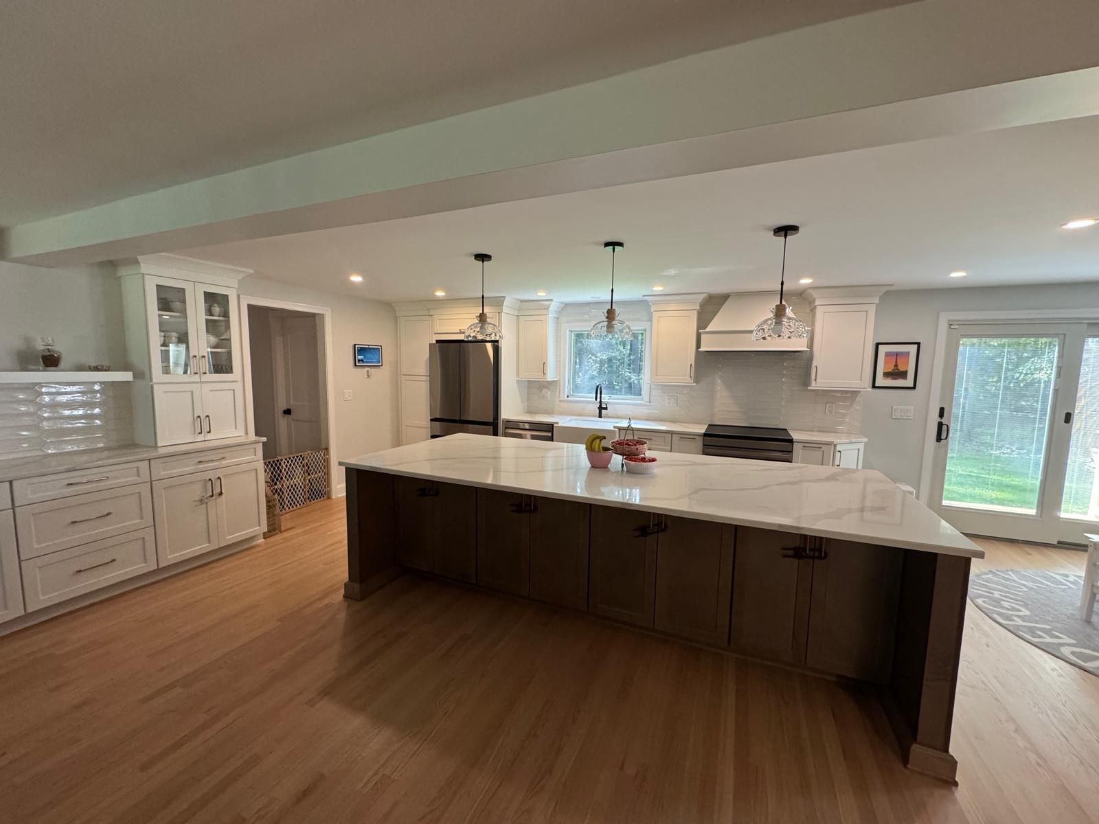 Spacious, light-filled kitchen with large island, white cabinets, and stainless steel appliances.