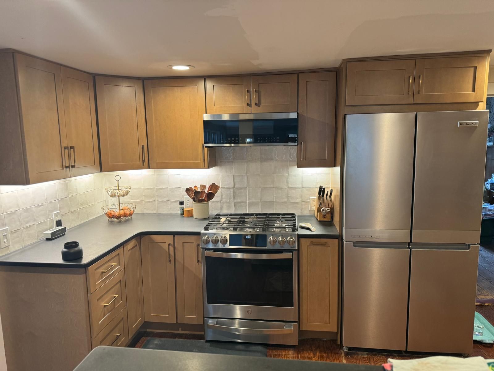 A kitchen with wooden cabinets, stainless steel appliances, and dark countertops.