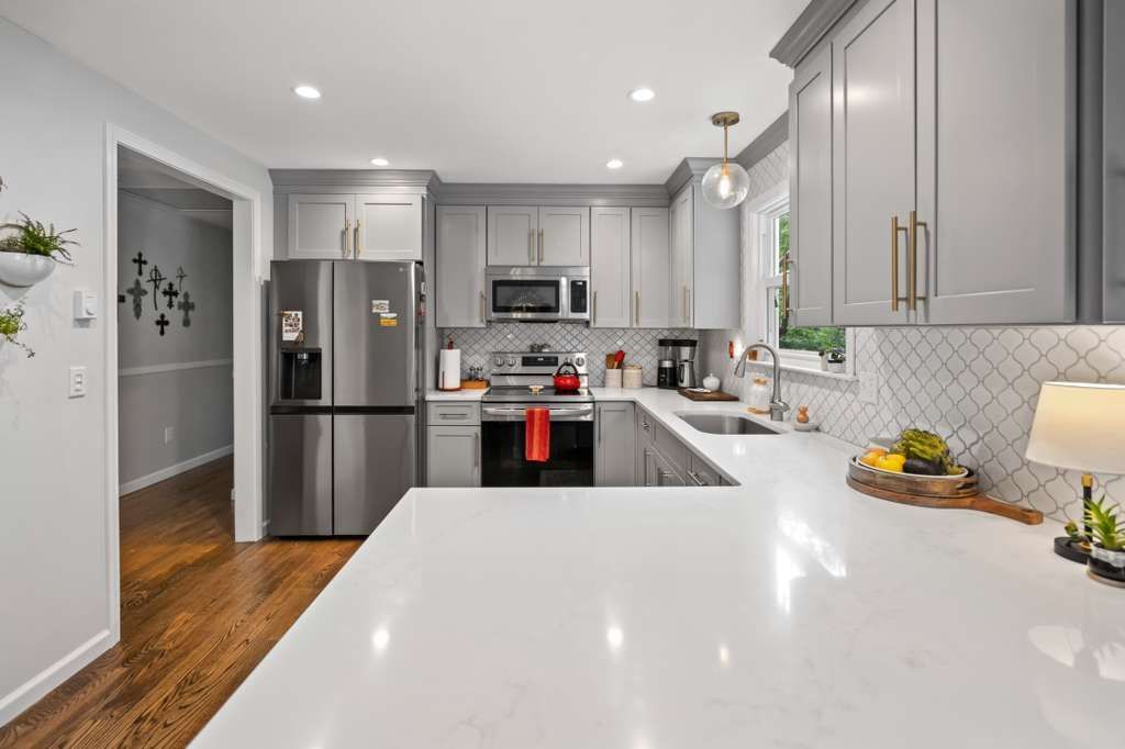 Gray kitchen with white countertops, stainless steel appliances, and wood floors.