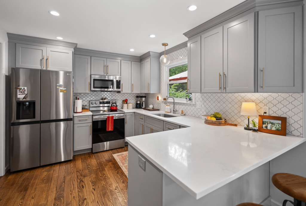 Gray kitchen with stainless steel appliances, white countertops, and wooden floors.