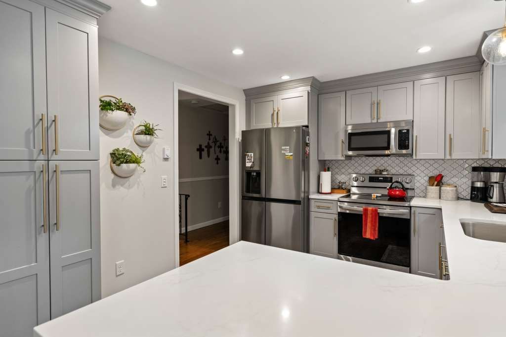 Gray kitchen with white countertop and stainless steel appliances; plants on wall.