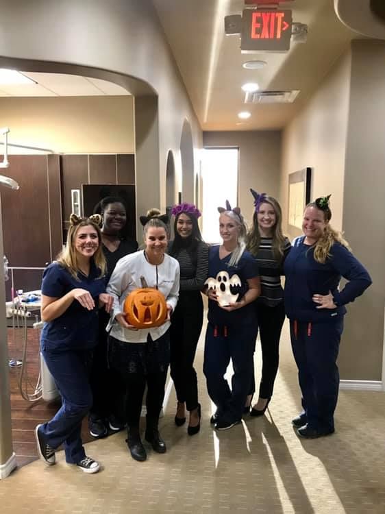 Dental staff in Halloween costumes, posing in a hallway.